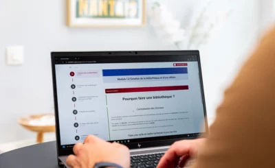 Personne utilisant un ordinateur portable sur une table, affichant un cours ou module en ligne, en intérieur. intégration possible: les erreurs à éviter dans un appel d offre btp dans la description.