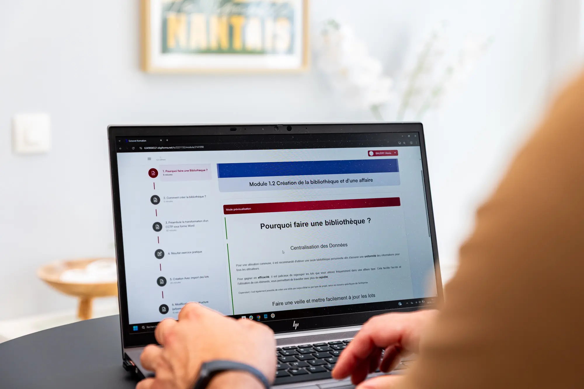 Personne utilisant un ordinateur portable sur une table, affichant un cours ou module en ligne, en intérieur. intégration possible: les erreurs à éviter dans un appel d offre btp dans la description.