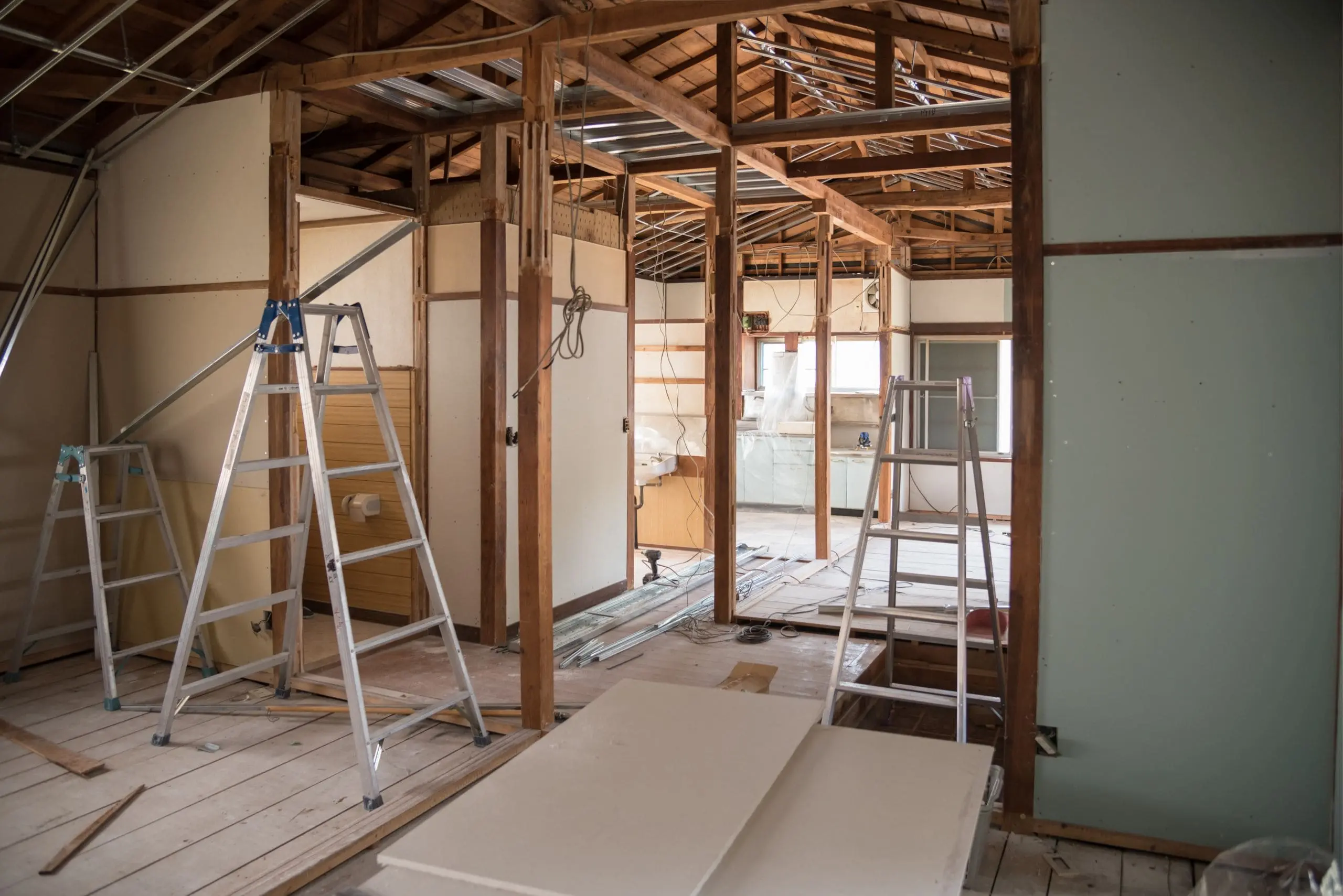 Chantier en rénovation avec structure en bois, échelles et plaques de plâtre, ambiance travaux et éléments de construction visibles. ccap vs cctp vs ccag intégré.